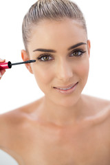 Smiling woman applying mascara