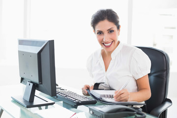 Obraz na płótnie Canvas Happy businesswoman arranging her diary at her desk