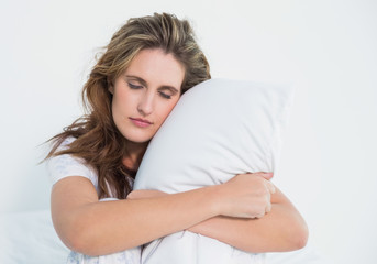 Fototapeta na wymiar Woman hugging pillow sitting on her bed