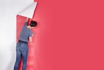 Woman hanging red wallpaper on white wall. Decorating or paperin