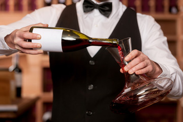 Sommelier with decanter. Cropped image of sommelier pouring wine - obrazy, fototapety, plakaty