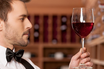 Confident sommelier. Side view of confident young sommelier hold
