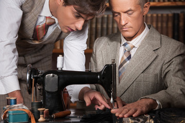 Tailors at work. Two confident tailors working at tailor shop