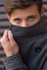Fototapeta premium Man in coat. Handsome young man adjusting his coat and looking a