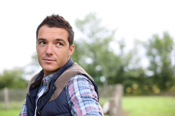 Man in countryside leaning on fence