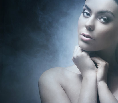 Portrait of a young and beautiful woman on a foggy background