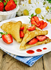 Pancakes with strawberries and jam on the board
