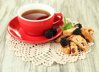 Cup of tea with cookies and blackberry on table close-up