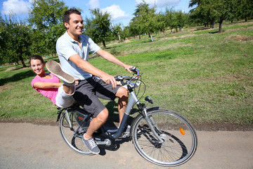 Obraz premium Cheerful young couple riding bikes in countryside