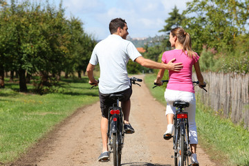 Naklejka premium Back view of man and woman riding bicycles