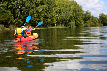 Couple riding canoe in river - obrazy, fototapety, plakaty