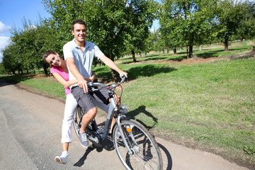 Obraz premium Cheerful young couple riding bikes in countryside