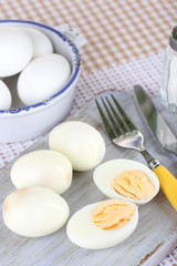 Boiled eggs on wooden board on tablecloth