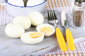 Boiled eggs on wooden board on tablecloth
