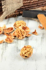 Broken walnuts with hammer on wooden table close-up