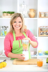 Happy smiling woman in kitchen preparing fresh fruit cocktail