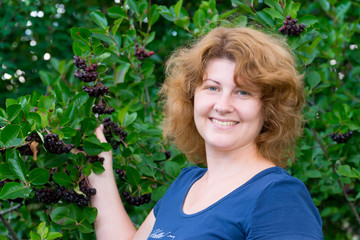 A woman in a black chokeberry bush in the garden