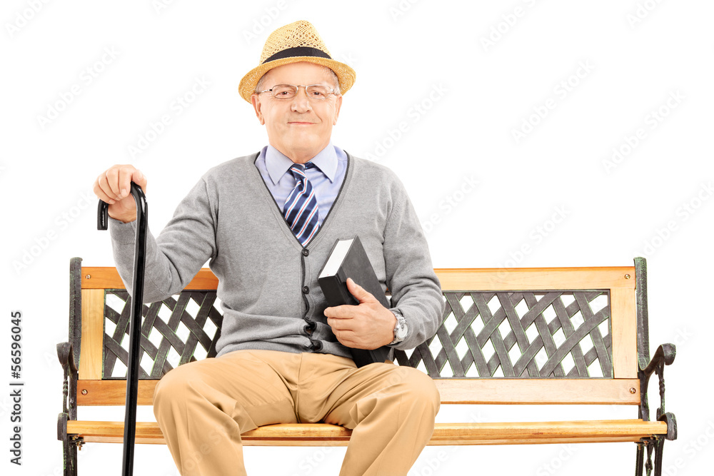 Wall mural senior man sitting on a wooden bench with book