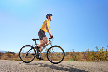 Young male with helmet riding a bike on a sunny day