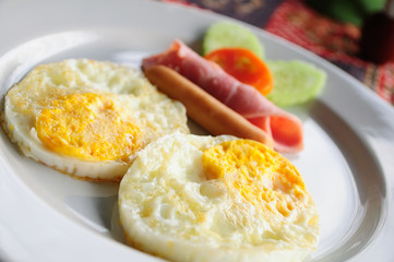 Breakfast meal, two eggs, ham and vegetables.