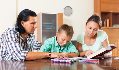 Obraz premium Schoolboy doing homework with parents