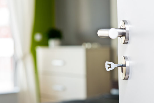 Detail of the key in the door with beautiful modern bedroom