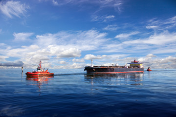 Tanker ship being guided into port by two tugs. - obrazy, fototapety, plakaty