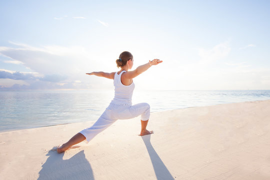 Caucasian woman practicing yoga at seashore