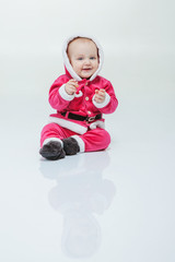 Small boy in Santa suit plays in white studio