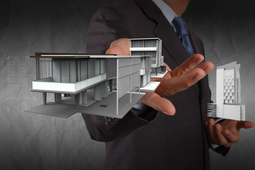 businessman hand shows house model with crumpled paper backgroun