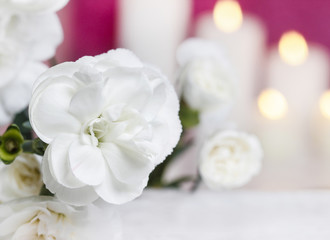 White carnation flowers. Candles in the background. Selective fo