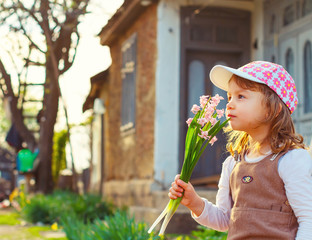 Adorable girl smelling flowers in a rustic garden