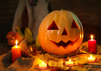 halloween pumpkin and autumn leaves, on wooden background