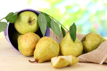 Pears in bucket on burlap on wooden table on nature background