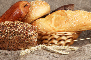 Baked bread in wicker basket on burlap background