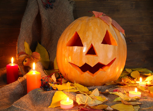 halloween pumpkin and autumn leaves, on wooden background