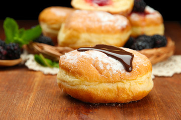 Tasty donuts with chocolate on wooden table