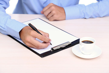 Businessman writing on document in office close-up