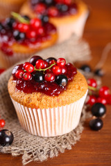 Tasty muffins with berries on wooden table