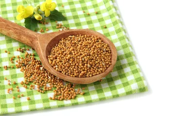 Poster Mustard seeds in wooden spoon with mustard flower isolated © Africa Studio