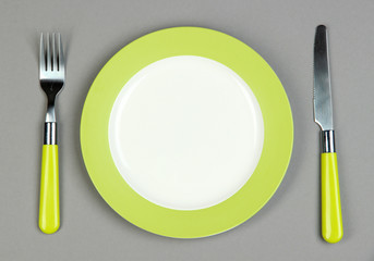 Knife, color plate and fork, on color background