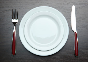 Knife, color plate and fork, on wooden background
