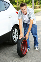 Man driver having trouble at road changing wheel