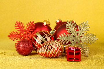 Christmas balls and small gift on yellow background
