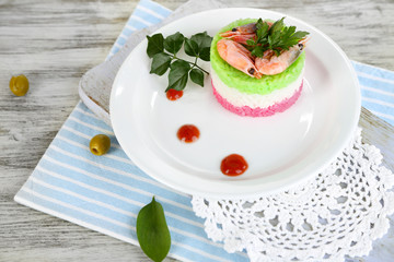 Colored rice on plate on board on napkin on wooden table