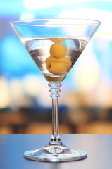 Martini with green olives on table in bar