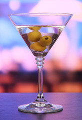 Martini with green olives on table in bar