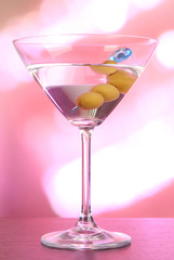 Martini with green olives on table in bar