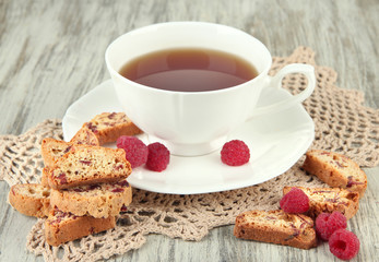 Cup of tea with cookies and raspberries on table close-up