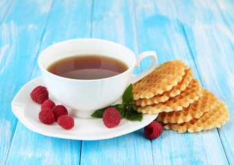Cup of tea with cookies and raspberries on table close-up